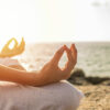 young woman meditation yoga pose on tropical beach with sunlight in background