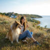 A young woman and an elderly dog walk in the countryside on a summer evening. A lady and her faithful friend from childhood a collie dog